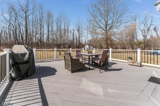 wooden deck featuring grilling area, an outbuilding, outdoor dining space, and a storage unit