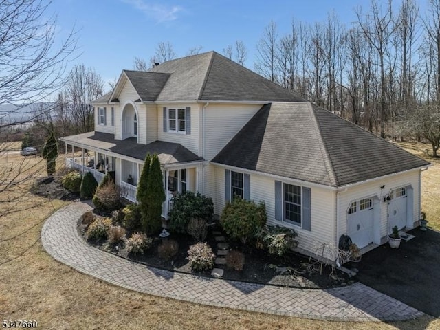 view of property exterior with a shingled roof, an attached garage, a porch, and driveway