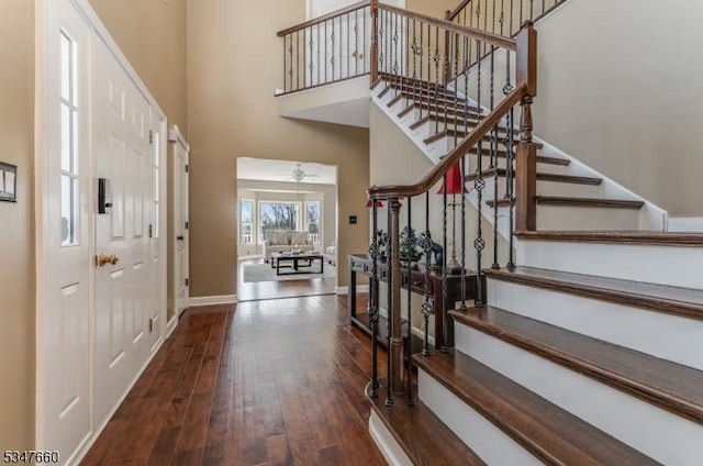 entrance foyer with baseboards, a ceiling fan, a high ceiling, stairway, and wood-type flooring
