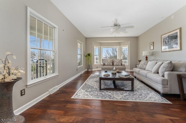 living area featuring wood finished floors, visible vents, a ceiling fan, and baseboards