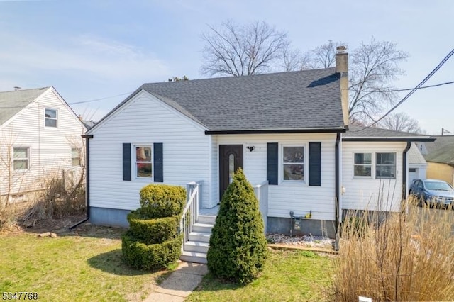 view of front of property with roof with shingles, a chimney, and a front lawn