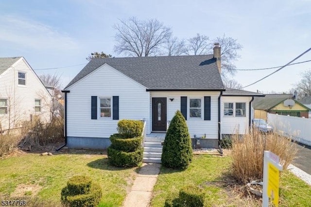 bungalow with a chimney, a shingled roof, a front yard, and fence