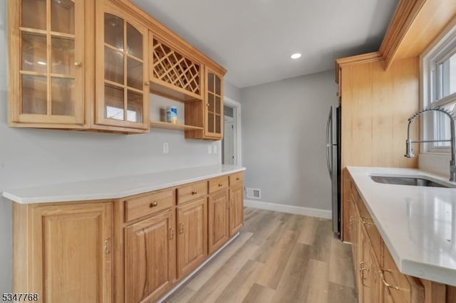 kitchen with freestanding refrigerator, light wood-type flooring, visible vents, light countertops, and a sink