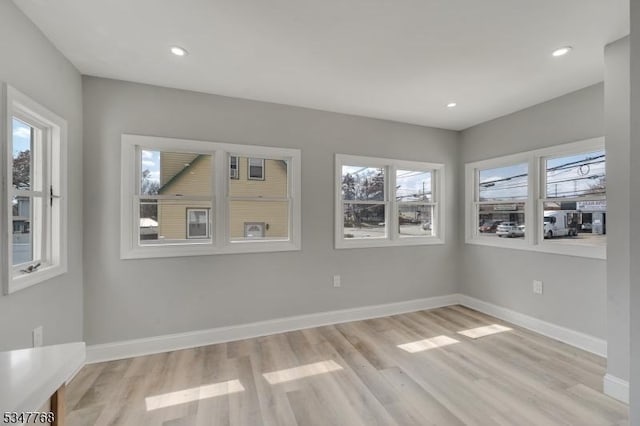 empty room featuring baseboards, plenty of natural light, and light wood-style floors