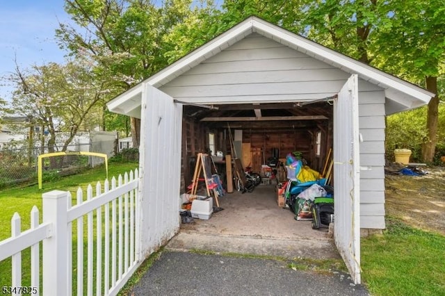 view of vehicle parking with fence and a detached garage