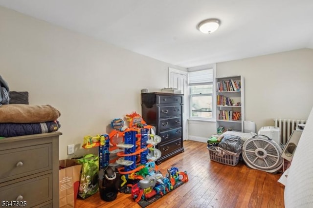 bedroom with baseboards, radiator heating unit, and wood-type flooring
