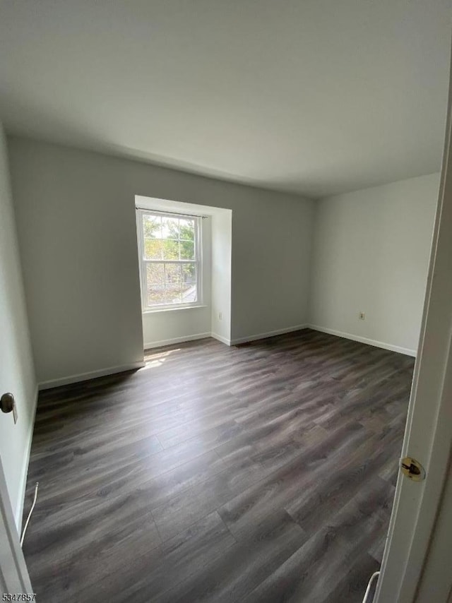 empty room with baseboards and dark wood-style flooring