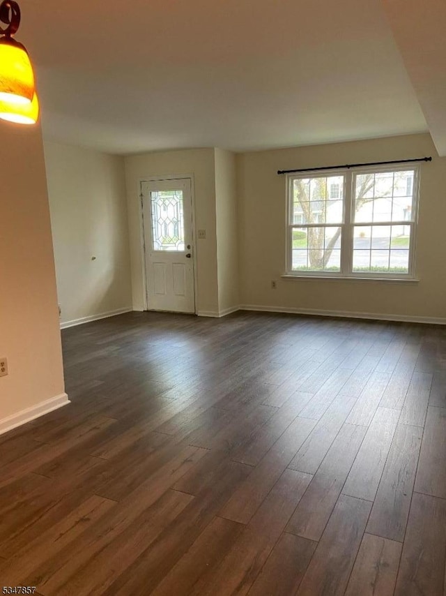 unfurnished living room featuring baseboards and dark wood-style flooring
