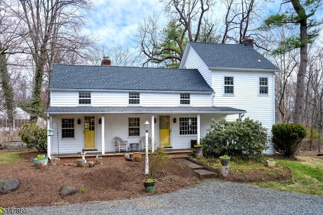 view of front facade featuring a porch, a chimney, and roof with shingles