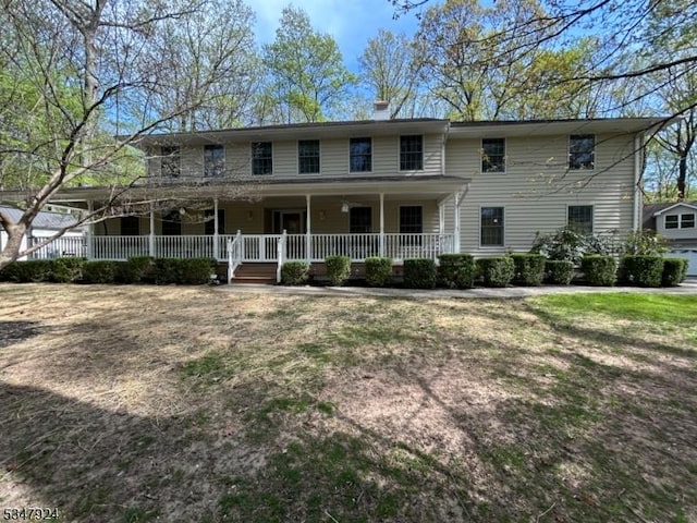 colonial inspired home with covered porch and a chimney