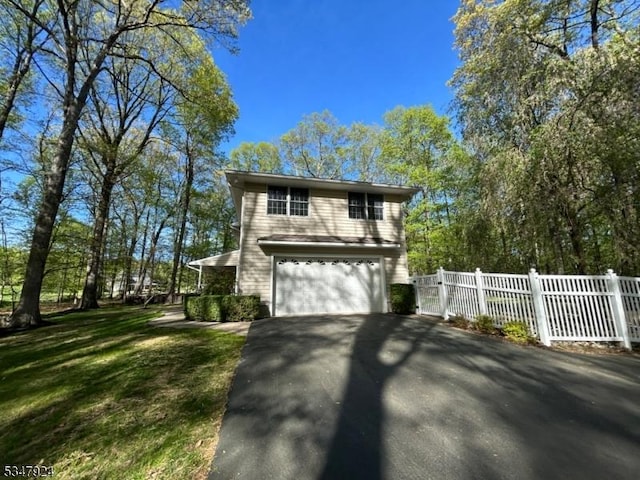 view of side of home with an attached garage, fence, and aphalt driveway
