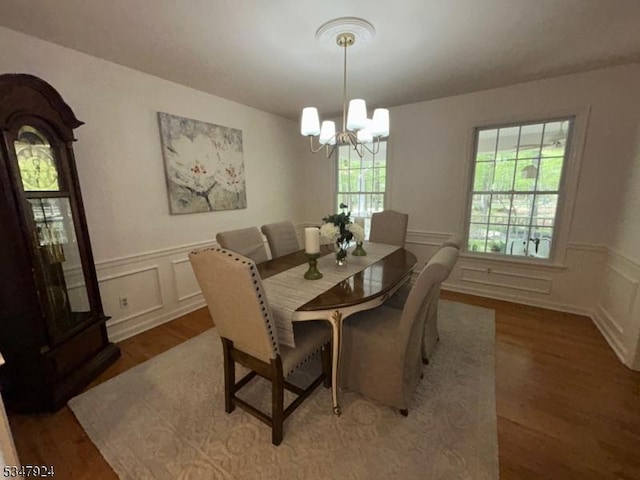 dining area featuring a chandelier, wainscoting, wood finished floors, and a decorative wall