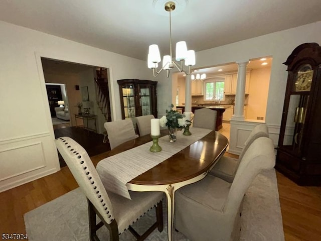 dining room featuring a chandelier, wainscoting, wood finished floors, and a decorative wall