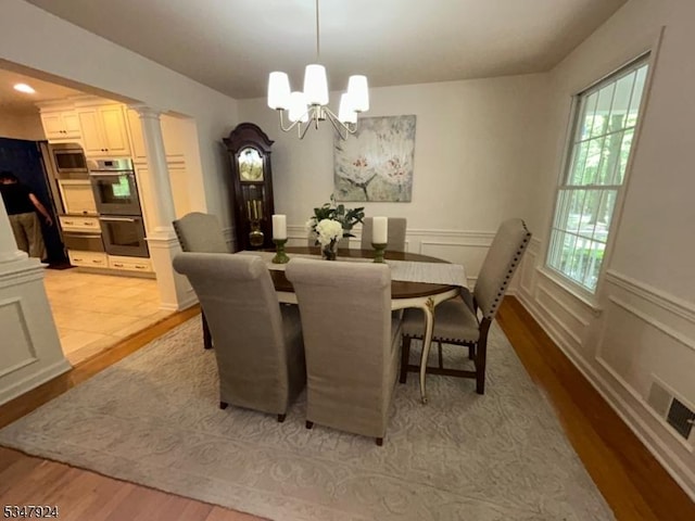 dining room featuring decorative columns, visible vents, light wood-type flooring, an inviting chandelier, and recessed lighting