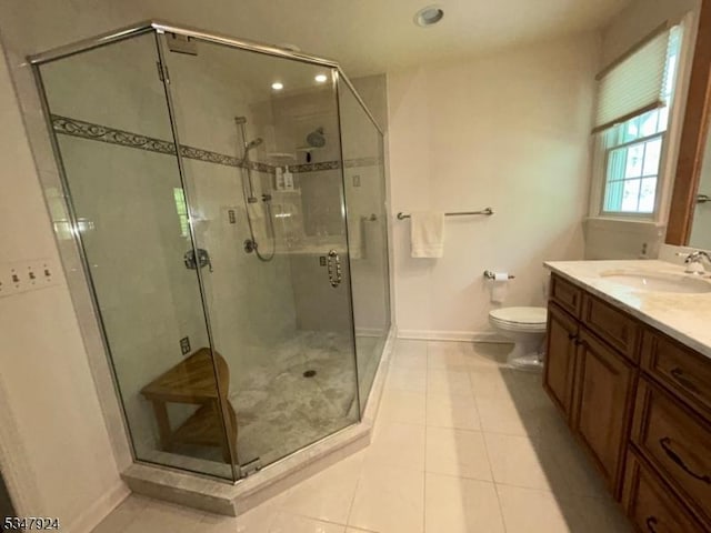 bathroom with vanity, toilet, tile patterned floors, baseboards, and a shower stall