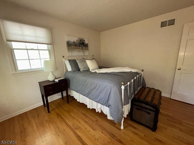 bedroom featuring baseboards, wood finished floors, and visible vents