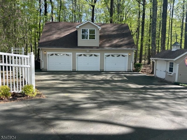 garage featuring aphalt driveway and fence