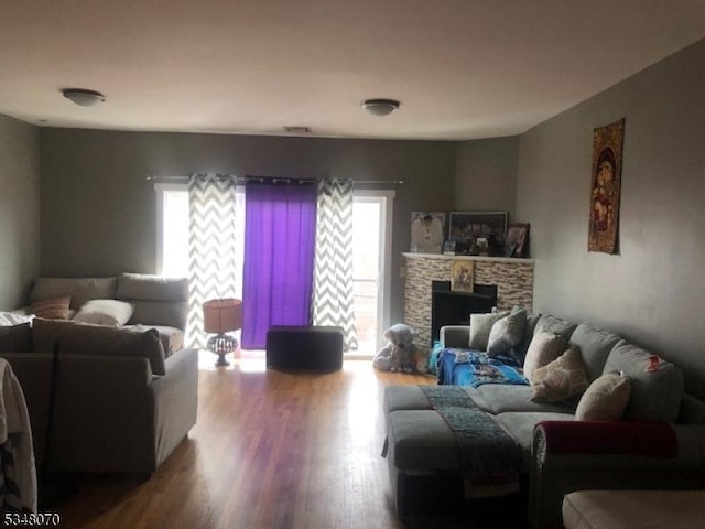 living area featuring a stone fireplace and wood finished floors