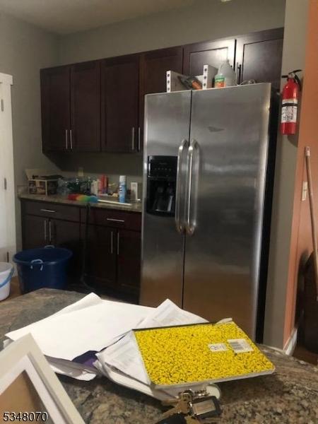 kitchen featuring stainless steel refrigerator with ice dispenser and dark brown cabinetry