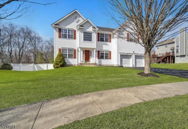 traditional-style house with a garage, stucco siding, a front lawn, and fence