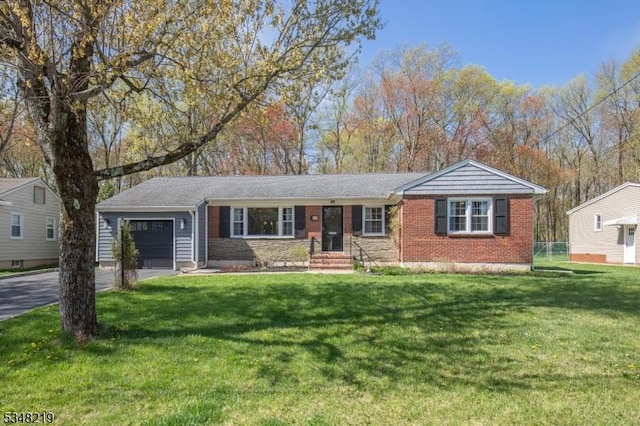 single story home featuring driveway, brick siding, a front yard, and an attached garage