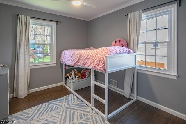 bedroom with crown molding, visible vents, wood finished floors, and baseboards