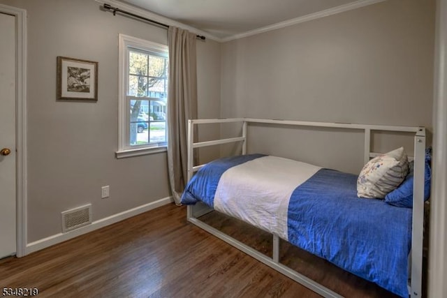 bedroom featuring wood finished floors, visible vents, ornamental molding, and baseboards