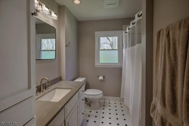 bathroom featuring toilet, vanity, tile patterned floors, and a healthy amount of sunlight