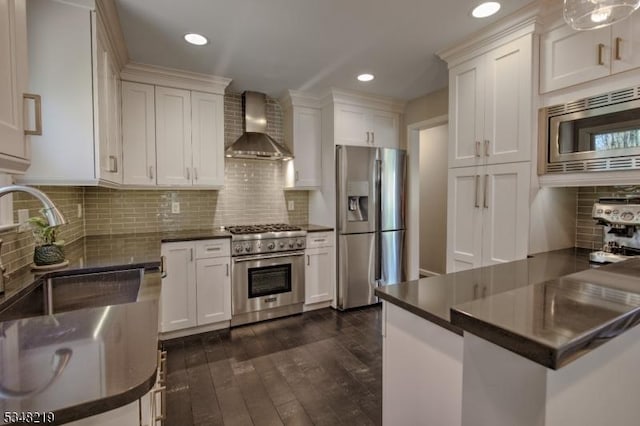 kitchen featuring a sink, wall chimney exhaust hood, dark countertops, and stainless steel appliances