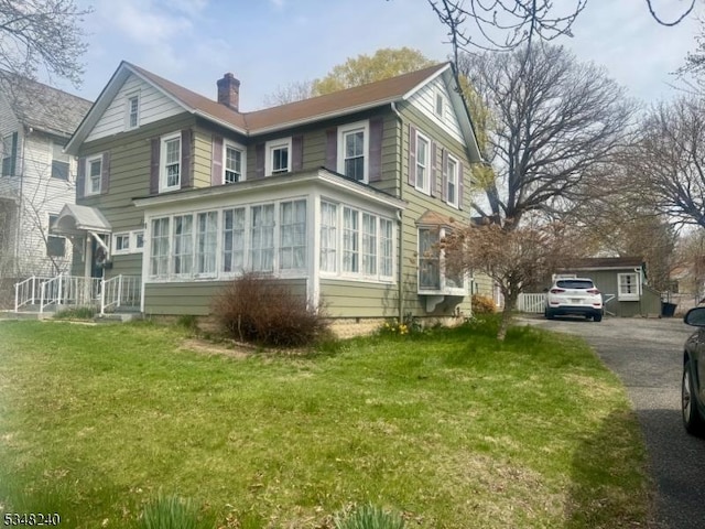exterior space featuring a yard, a sunroom, and a chimney