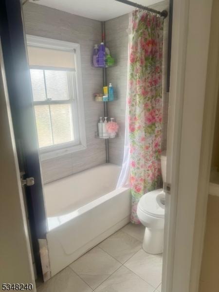 bathroom featuring tile patterned floors, shower / bathtub combination with curtain, and toilet