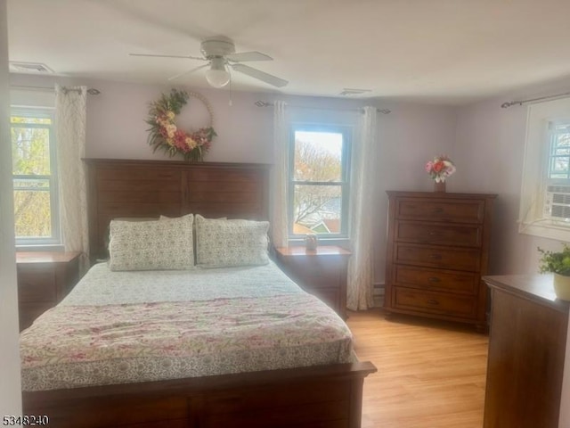 bedroom featuring light wood finished floors, a ceiling fan, and multiple windows