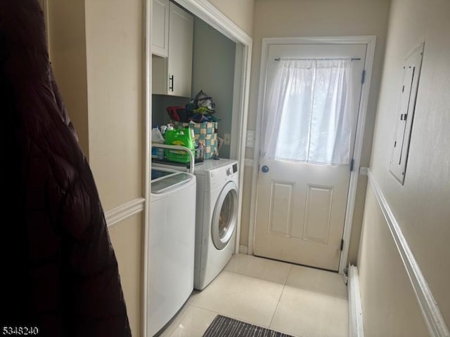 clothes washing area featuring washing machine and dryer, electric panel, light tile patterned floors, and cabinet space