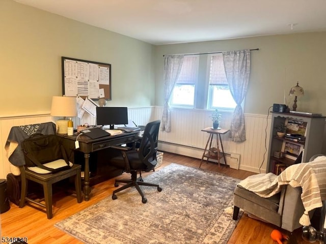 home office featuring a baseboard heating unit, wood finished floors, and a wainscoted wall