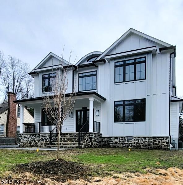 modern inspired farmhouse featuring a front yard, a porch, and board and batten siding