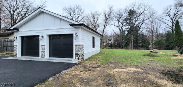 exterior space featuring an outdoor structure, fence, a detached garage, and board and batten siding