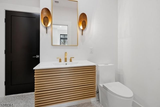 bathroom with speckled floor, toilet, and vanity