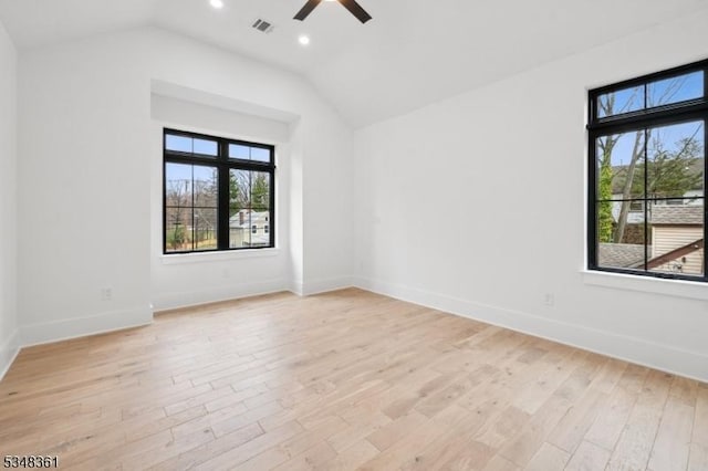 empty room featuring visible vents, light wood-style flooring, baseboards, a ceiling fan, and vaulted ceiling