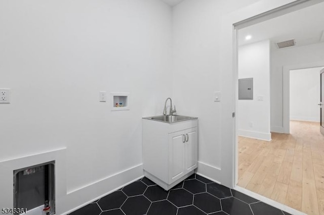 laundry area featuring baseboards, a sink, visible vents, laundry area, and electric panel