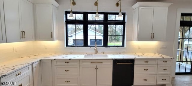kitchen with decorative backsplash, white cabinets, black dishwasher, a sink, and light stone counters