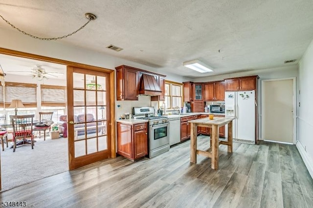 kitchen featuring dishwasher, stainless steel gas range oven, white refrigerator with ice dispenser, and a textured ceiling