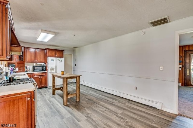 kitchen featuring black microwave, white refrigerator with ice dispenser, visible vents, and light wood-style floors