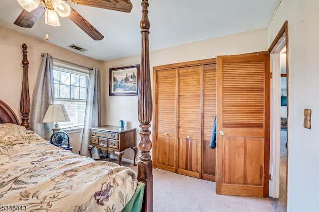 bedroom with light colored carpet, a ceiling fan, visible vents, and a closet