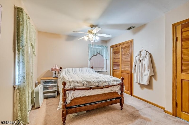 bedroom featuring light carpet, baseboards, visible vents, a ceiling fan, and a closet
