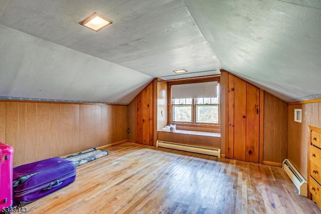 bonus room featuring a baseboard heating unit, visible vents, wood finished floors, wood walls, and a baseboard radiator
