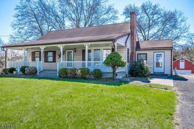 view of front facade with a detached garage, a chimney, a front yard, and covered porch