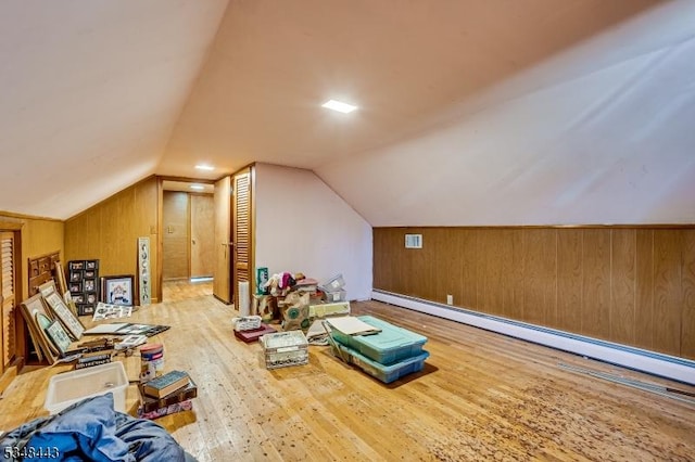 bonus room featuring a baseboard heating unit, vaulted ceiling, wood walls, and wood finished floors