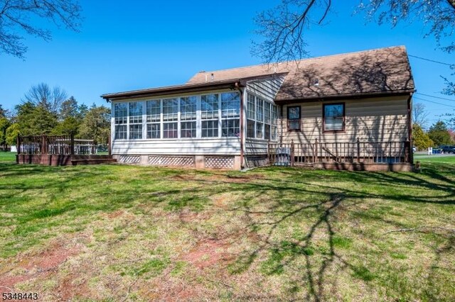 rear view of house featuring a shingled roof, a sunroom, and a yard