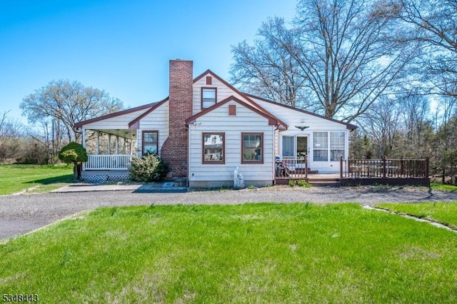 view of front of home with a chimney, a deck, and a front yard