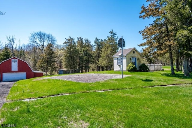 view of yard with a detached garage, an outdoor structure, driveway, and a barn